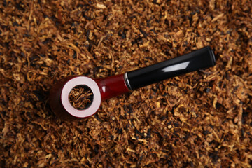 Smoking pipe on pile of tobacco, top view