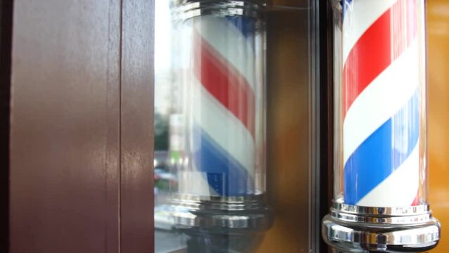 the barber's sign, Barber's pole, hangs on the wall at the entrance to the barber's shop. The three-color ribbon is spun in a plastic glass tube. Red blue white closeup