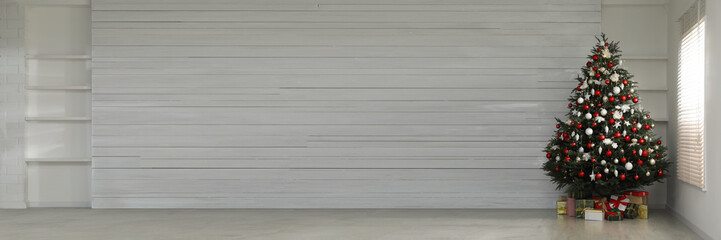 Beautifully decorated Christmas tree and gift boxes indoors, space for text. Banner design