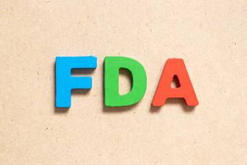 Color alphabet letter in word FDA (abbreviation of food and drug administration) on wood background