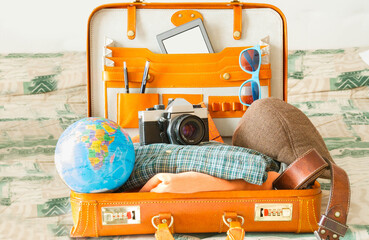 A vintage camera, the globe, glasses, and an open suitcase full of other travel items.