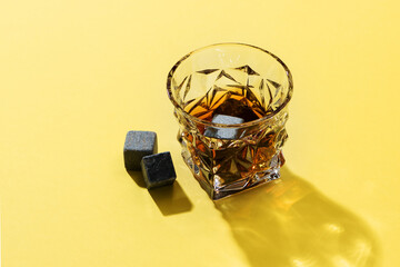 Hard strong alcoholic drinks in glass: cognac, tequila, scotch, brandy or whiskey on a yellow background with hard lights and shadows, top view