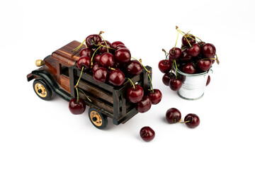 Ripe sweet cherries in a wooden toy truck on white background.