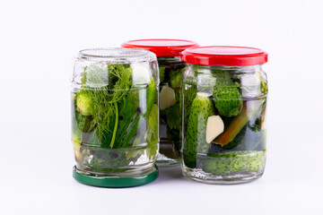 Pickled cucumbers in glass jar on white background.