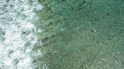 Aerial top view of a male surfer swimming in a tranquil water
