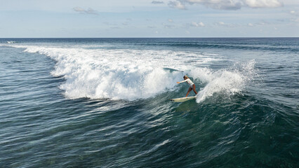 Aerial view of a female surfer riding the huge waves