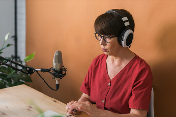 Middle-aged female radio presenter talking into the microphone and reading news - radio broadcast...