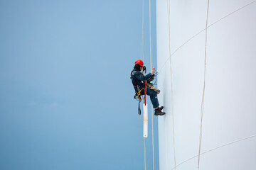 Male workers down height tank rope access inspection of thickness shell plate storage tank.