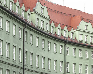 Side shot of an old green building with a red r
