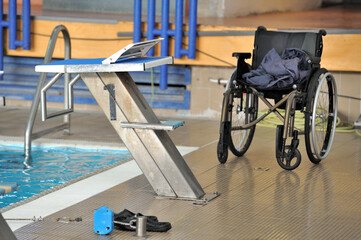 Piece of cloth on a wheelchair next to a Swimming pool - obrazy, fototapety, plakaty