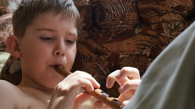 Portrait. caucasoid teenage boy plays the armenian wind instrument sring lying in a chair. Studying the national music of different countries, slow motion