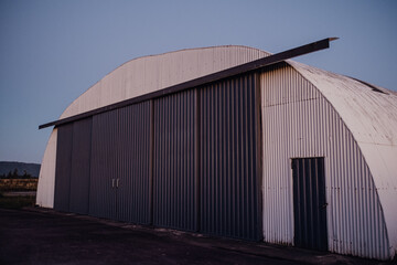 Big metal arched hangar countryside on a blue sky background
