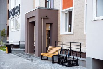 Fototapeta na wymiar Entrance of a new modern residential apartment building with parking for bicycles and a bench. Concept of modern apartments