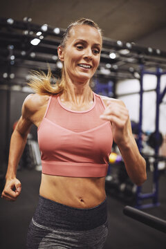 Smiling mature woman running on a treadmill in a gym