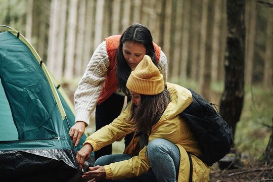 Women putting up a tent in the forest