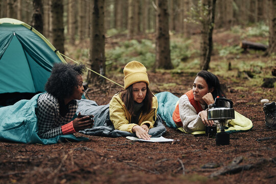 Diverse friends checking a map while camping