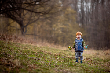 A little boy runs in the park with the flag of Ukraine and holds a bouquet of spring flowers