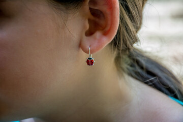 Ladybug earring on the female ear © Dreser/Wirestock Creators