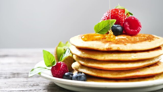 stack of pancake with pouring maple syrup