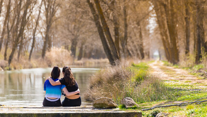 Two friends sitting on a jetty at the end of a road