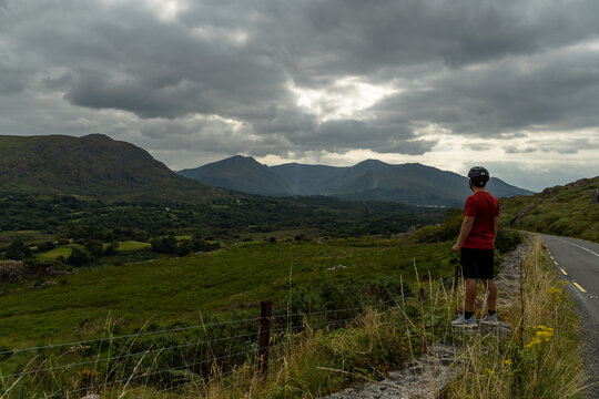 Young Caucasian cyclist on the sideroad looking at the mountains on the Beara peninsula Ireland