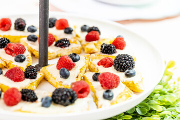A closeup of homemade fruit tarts covered in raspberries, blackberries, and blueberries.