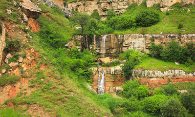 Fototapeta premium Beautiful waterfall with red mountains in the gorge.