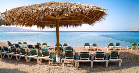 Morning on a public beach with umbrellas and deck chairs in Eilat - famous tourist resort in Israel, Middle East