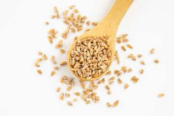 Wooden spoon with whole grain wheat groasts on a white isolated background,top view