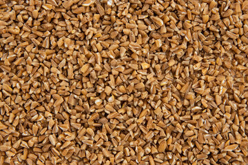 Handful of crushed whole wheat grain background,top view.