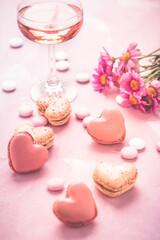 Happy Mothers Day - sweet macarons and glass of rose sparkling wine with flowers in pink tone