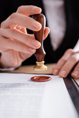 close up view of cropped notary stamping contract with wax seal.