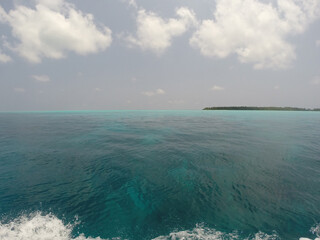 Maldives. Indian Ocean. Blue sky. Blue turquoise water. Island in the distance.