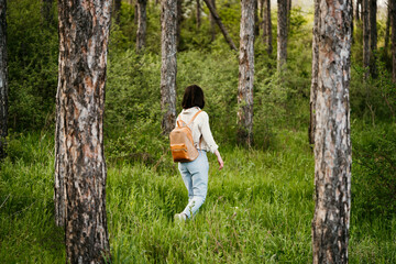 Naklejka premium Young woman with backpack walking alone in a forrest