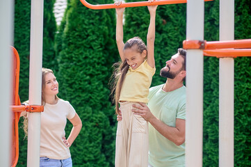 Obraz premium A family having fun at the sports gound on horizontal bar