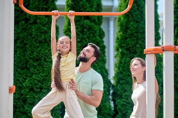 Obraz premium A family having fun at the sports gound on horizontal bar