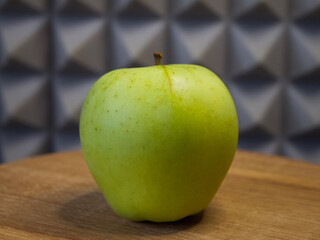 One large apple on a wooden surface, side view. Apple close-up.