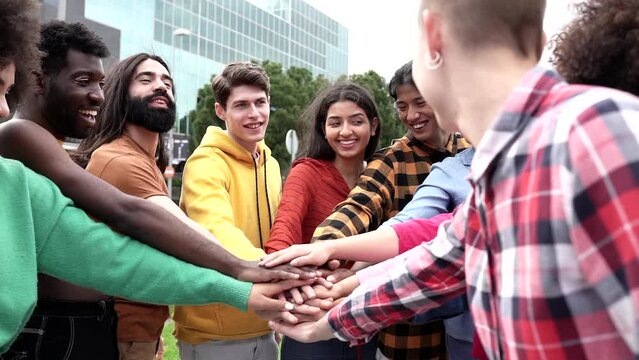 group of multiracial friends outdoors put their hands together and applaud, Young diverse team having fun stacking hands outdoor