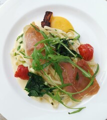 Top view of gourmet pasta dish with parma ham and cheese sauce