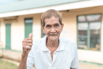 Portrait of an old asian teacher in front of a small preschool. A veteran principal at a small...