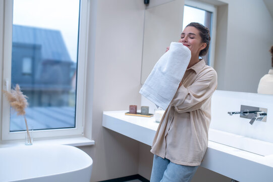 A woman smelling fresh towel after washing