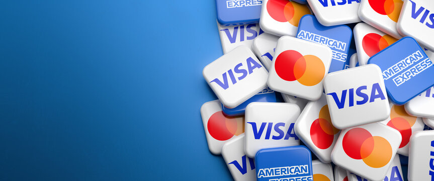 Logos of the competing credit card companies Visa, Mastercard and American Express on a heap on a table. Copy space. Web banner format.