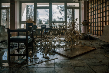 Abandoned canteen in an old pioneer camp. Broken furniture. Light from windows. Empty abandoned place. Dirty and shabby walls. Old interior of an abandoned building.