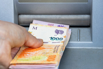 Woman takes Argentine money from ATM, Thousand pesos banknote, Highest denomination, Financial...