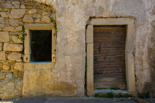 An old wooden door and empty window in an historic derelict farm building in the village of Roc near Buzet in Istria, western Croatia 
