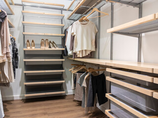 A large, walk in closet with shirts and pants hanging up on hangers and shoes on the shelving