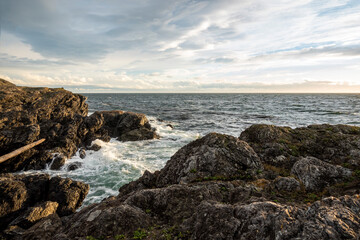 White, foamy waves crashing against coastal rocks at sunset on San Juan Island, WA