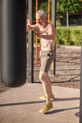 A mature gray-haired man exercising in the park