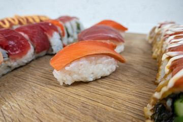 Angled, selective focus view of a variety of sushi rolls on a bamboo cutting board