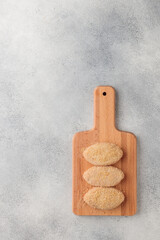 Raw beached meat cutlets on a wooden board